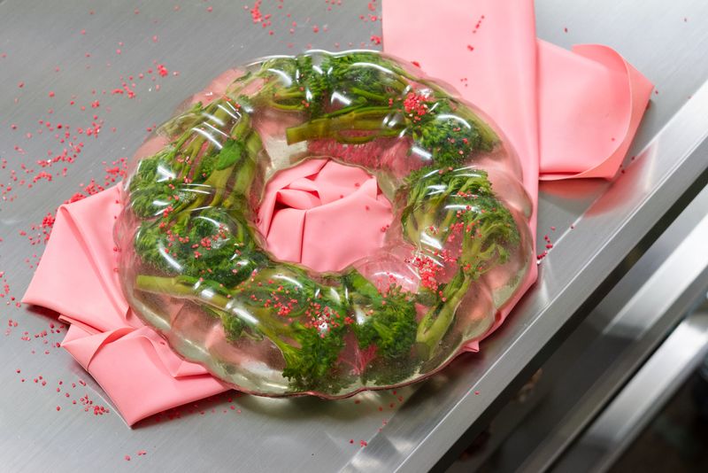 Close up of Natalia Janula's work brocoli cast in cake mould shaped resin lying on pink latex ribbon